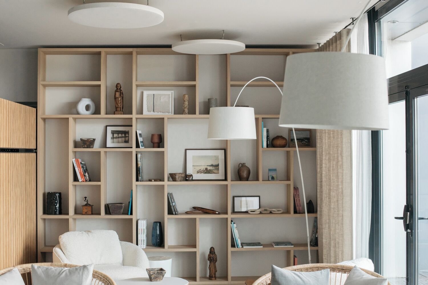 Un salon moderne avec une grande bibliothèque, un canapé blanc et un grand lampadaire.