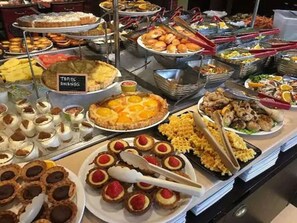 Un bufé con diversos alimentos, entre ellos tartas, pasteles y mariscos.