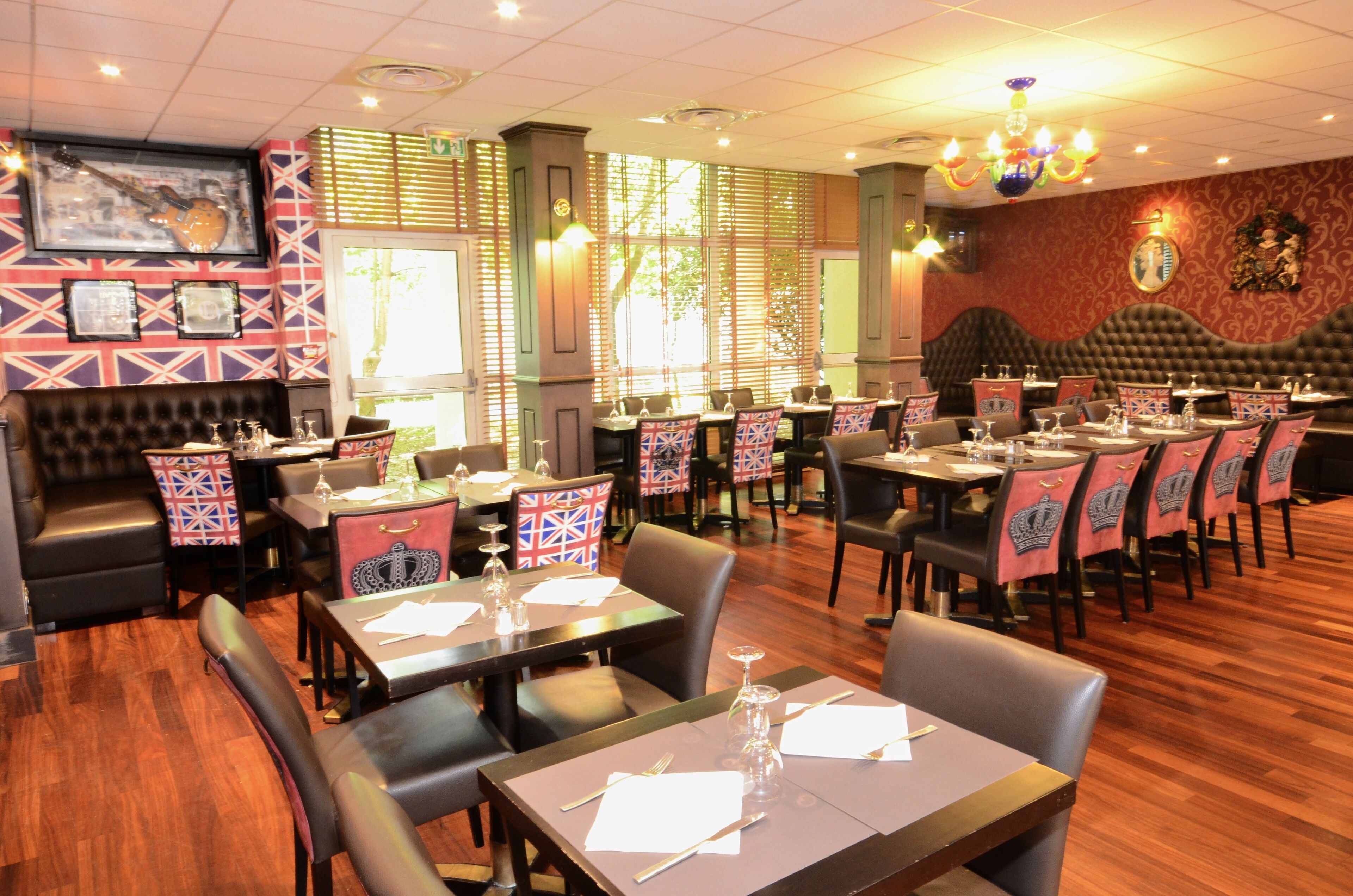 A restaurant with multiple tables and booths, wooden flooring, and patterned tablecloths.