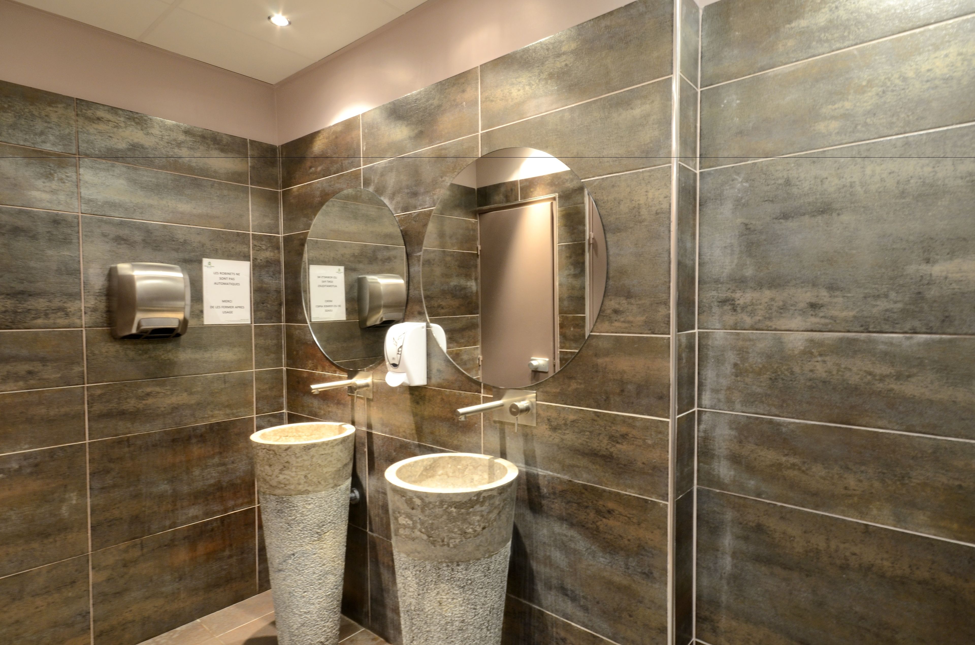 Un baño moderno con dos lavabos, un secador de manos y un espejo.