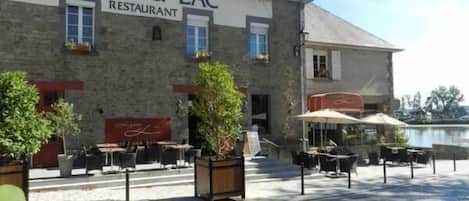 A building labeled "HOTEL DU LAC RESTAURANT" with outdoor seating and a view of water.