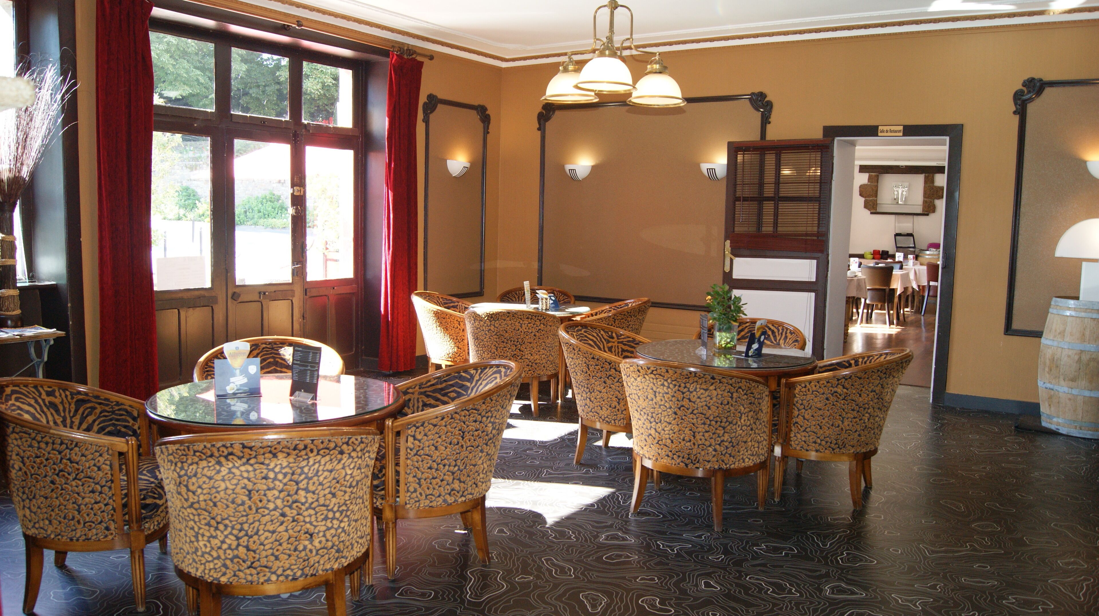 A dining area with round tables and chairs, a wooden floor, and a view of the outdoors through a window.