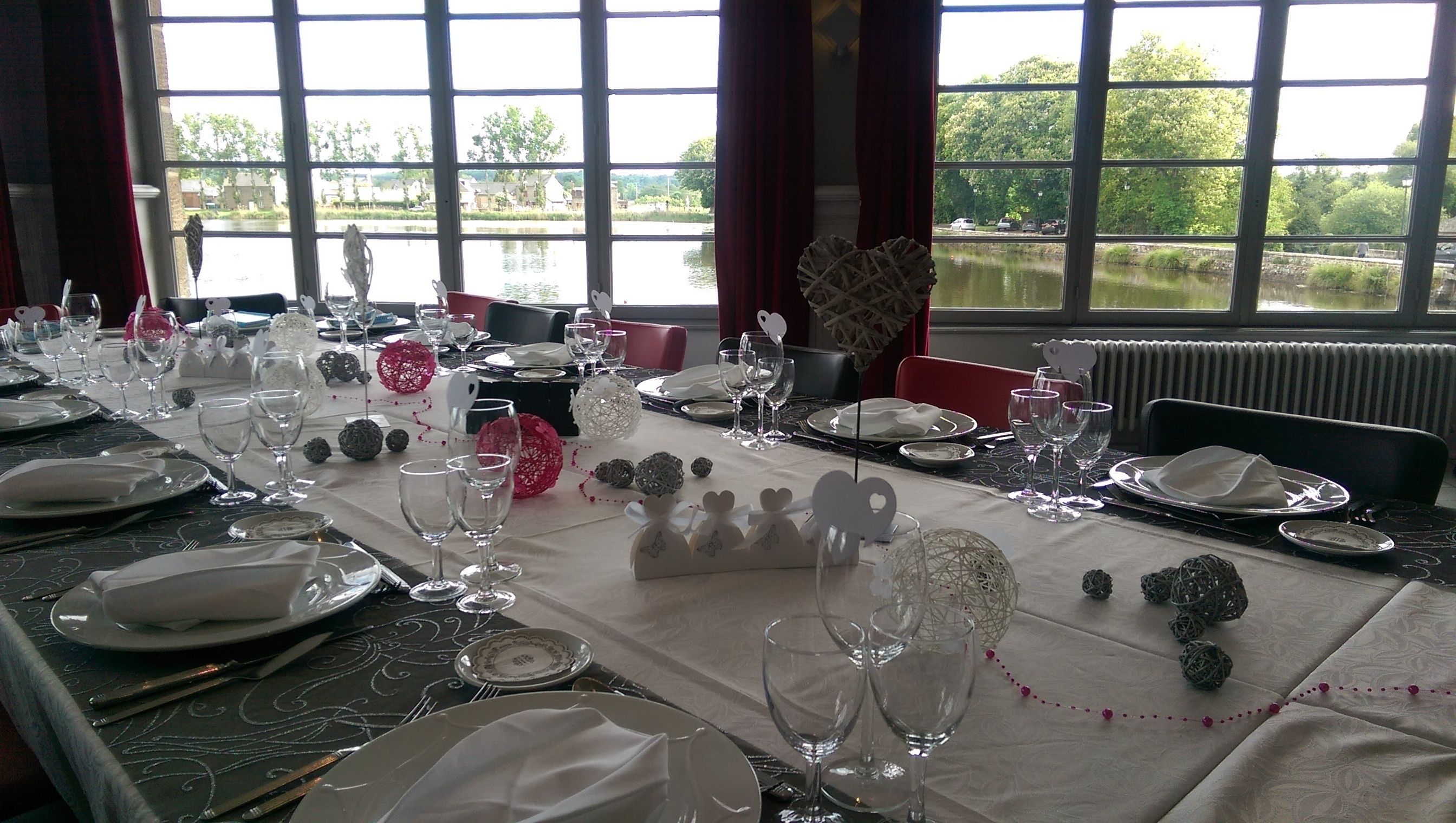 A dining table set for a meal with a view of a lake and buildings in the background.