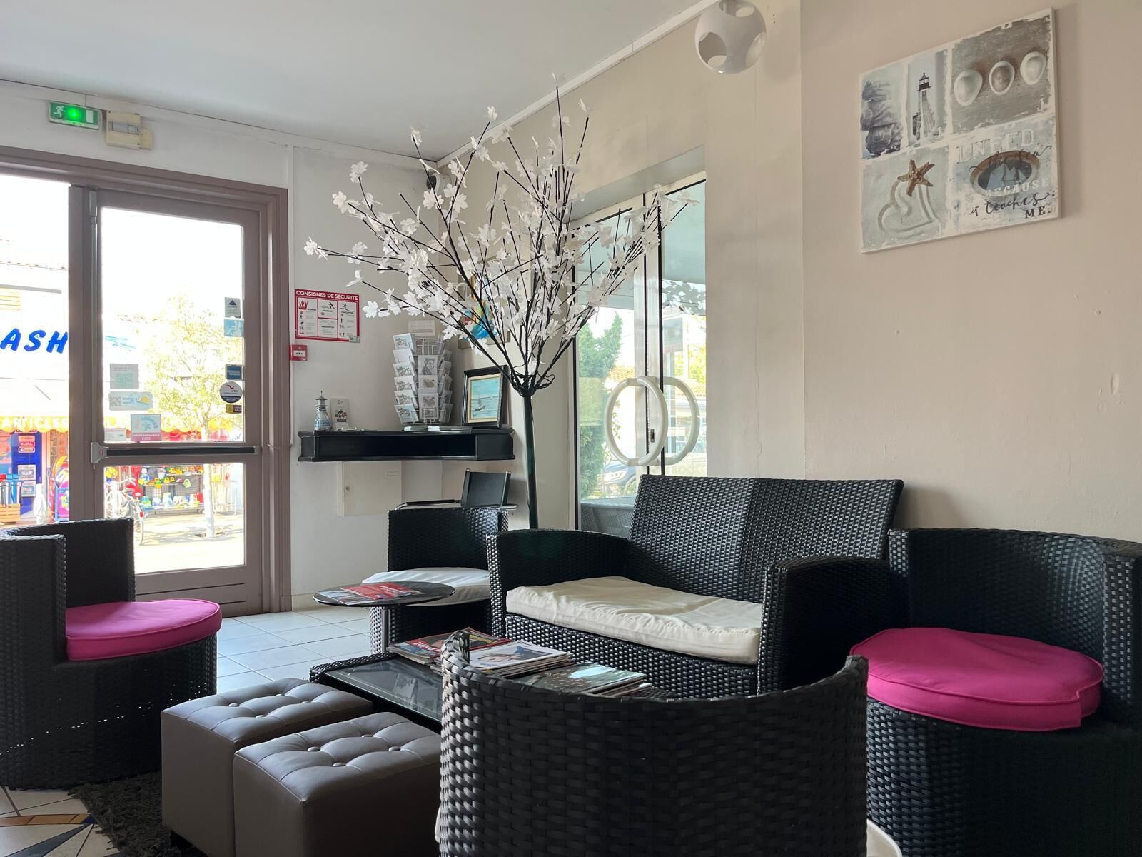 Une pièce avec un canapé en osier, une table basse et un vase décoré de branches.