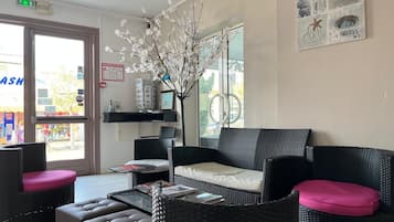 Una habitación con un sofá de mimbre, una mesa de centro y un jarrón con ramas.