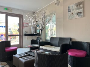 A room with a wicker sofa, a coffee table, and a vase with branches. - Hôtel de la Mer (La Tranche-sur-Mer)