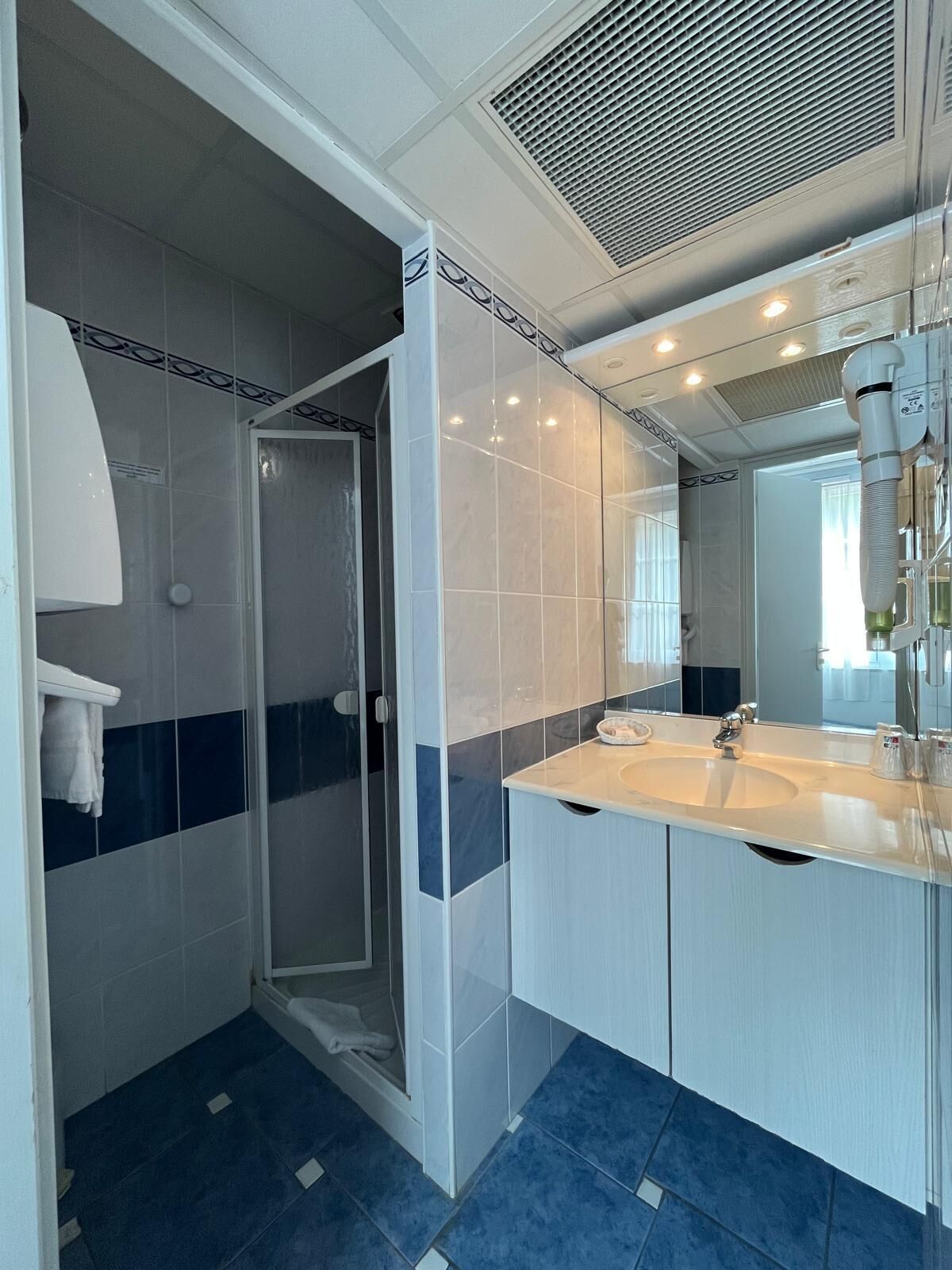 A modern bathroom with a walk-in shower, a large mirror, and a dual sink vanity.