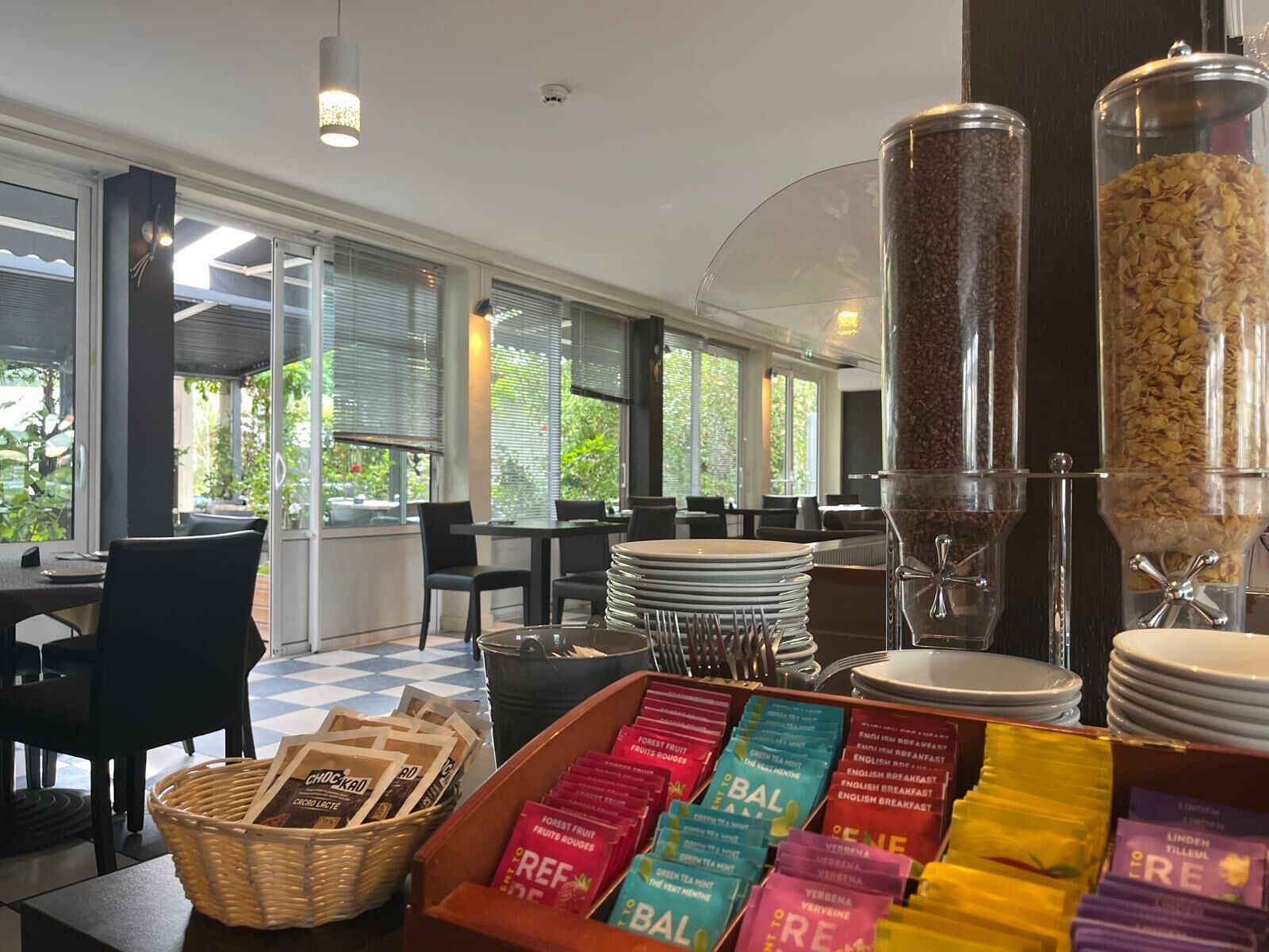 A breakfast buffet area with various food items and beverages, including cereal and tea options.