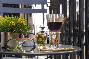A table with a potted plant, a glass of red wine, a glass of olive oil, a pair of glasses, and some cookies. - Hôtel Phileas Lazare & Spa - Opéra (Paris)