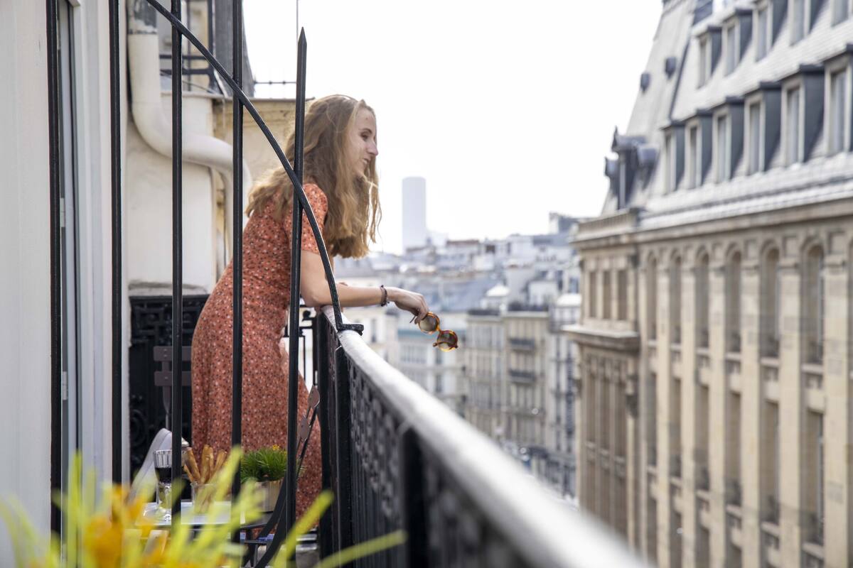 A person on a balcony overlooking a cityscape with historic buildings.