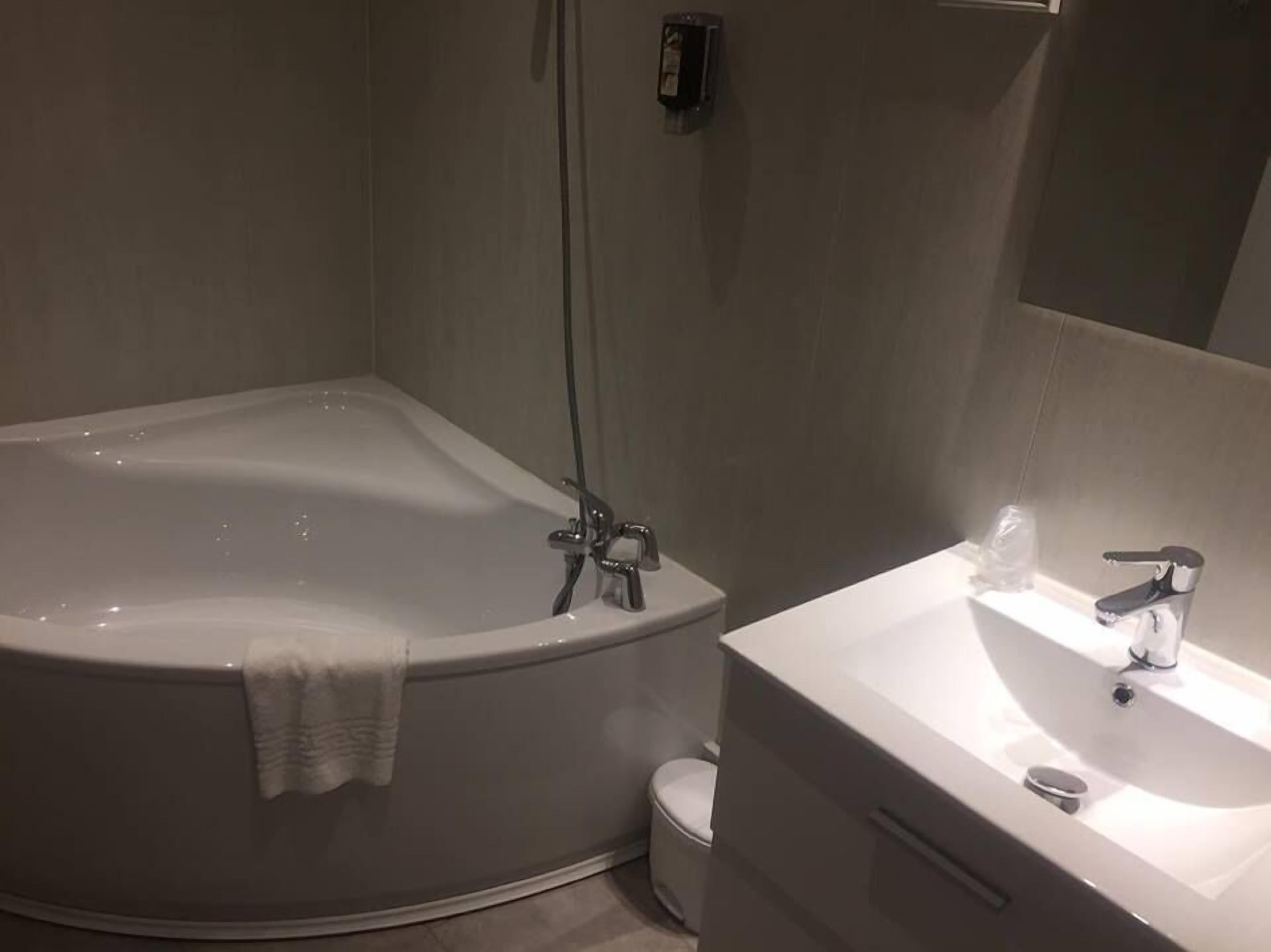 A modern bathroom with a freestanding bathtub, a toilet, and a sink with a mirror.
