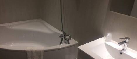 Un baño moderno con una bañera independiente, un inodoro y un lavabo con espejo.