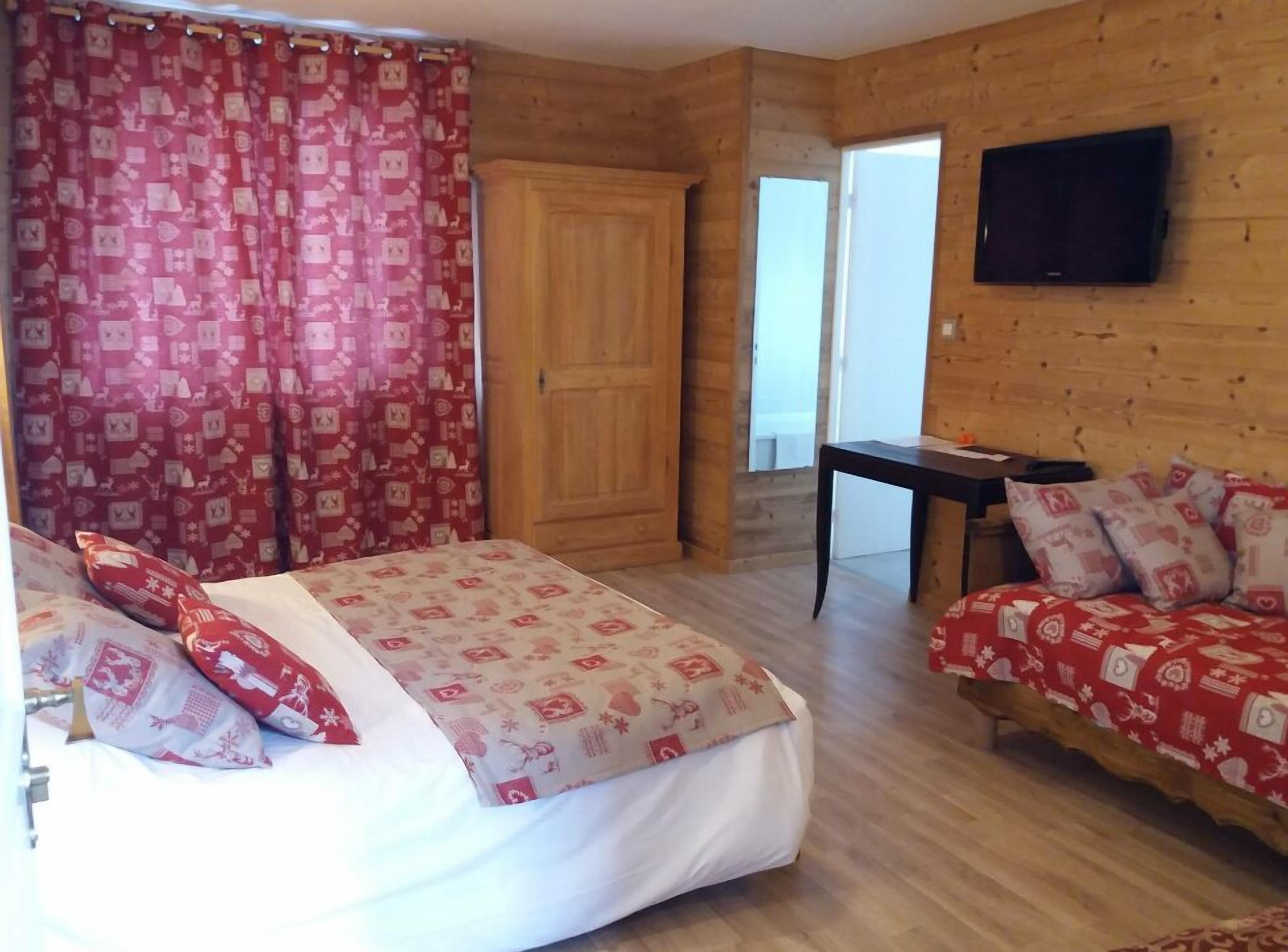 Una habitación con una cama, una mesita, un televisor y una puerta.