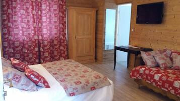 Una habitación con una cama, una mesita, un televisor y una puerta.