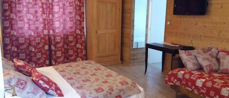 A room with a bed, a small table, a TV, and a door.