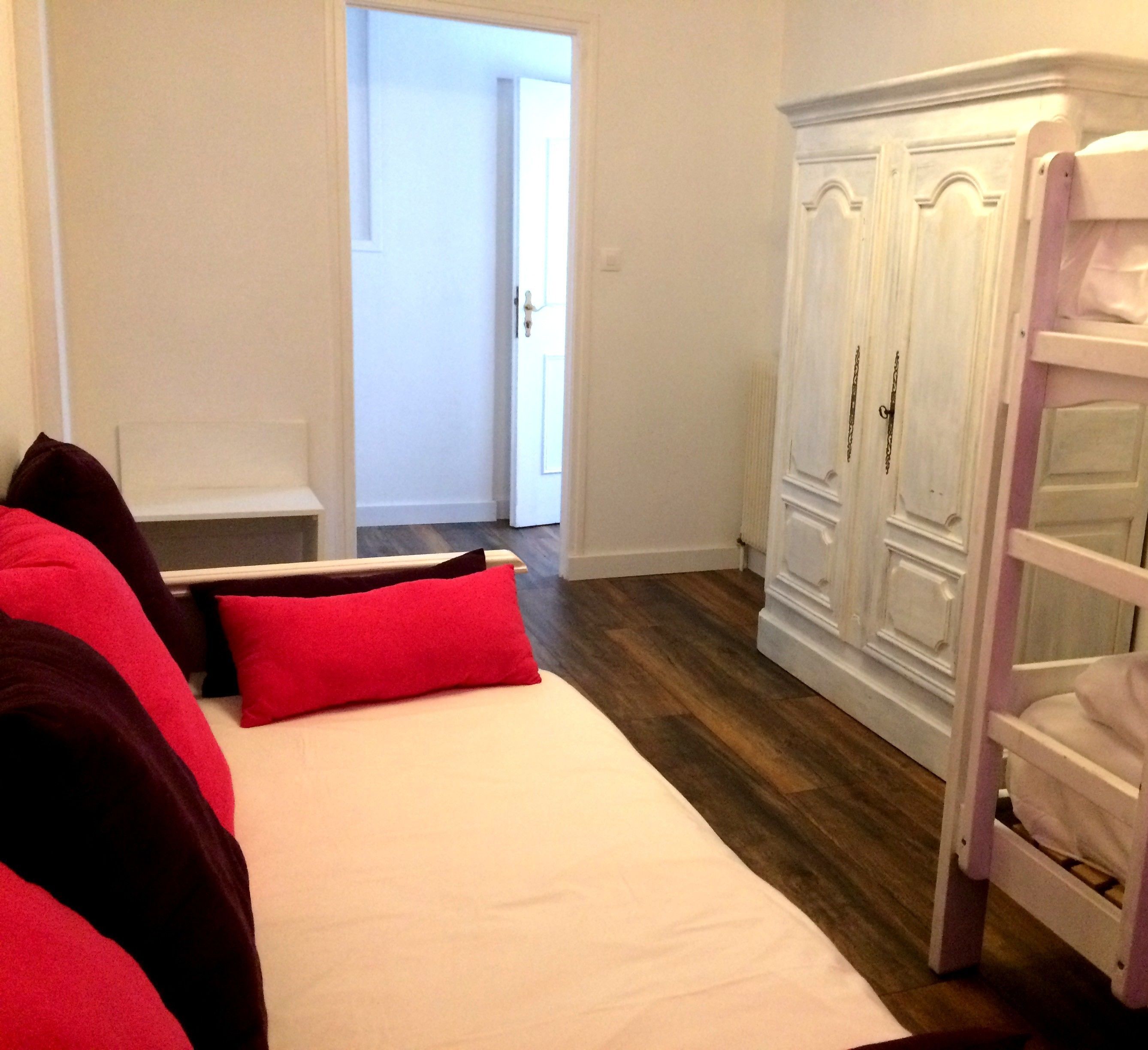 A bedroom with a bed, a wardrobe, and a door leading to another room.