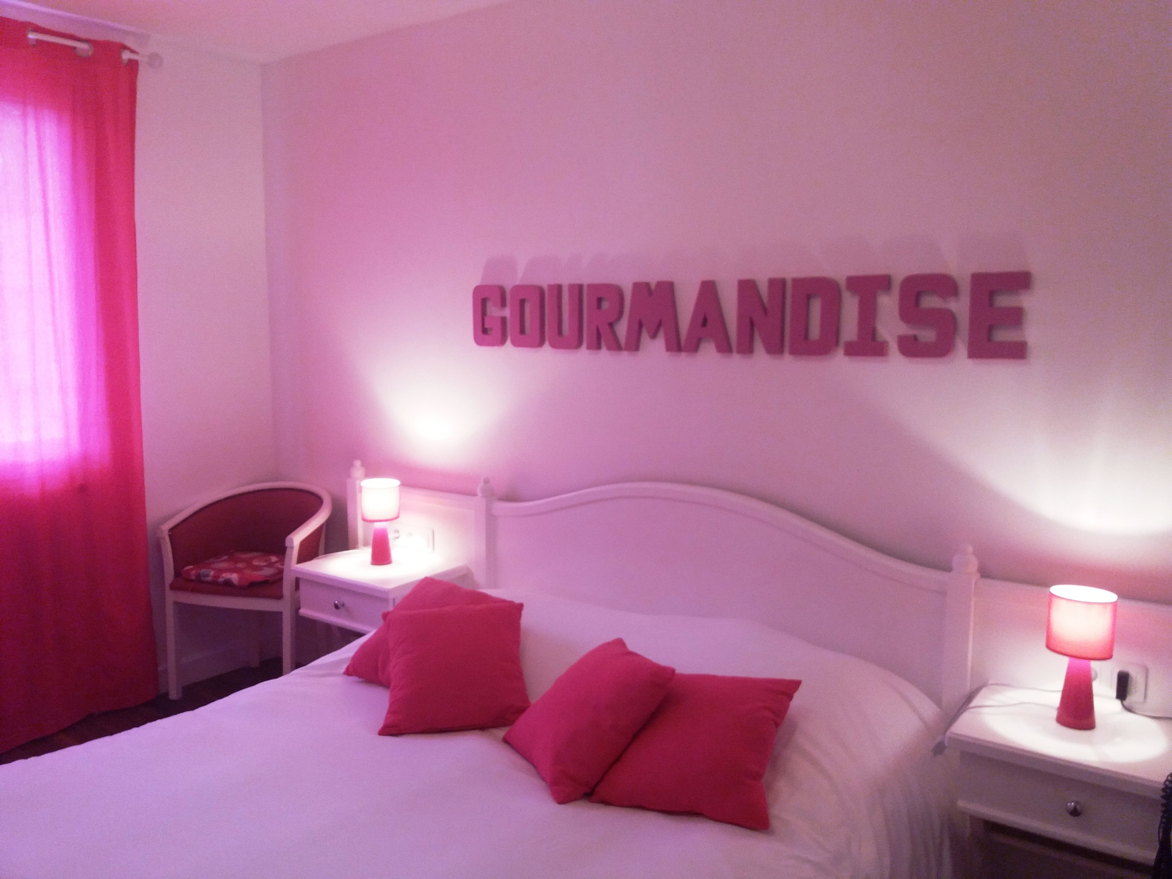 A bedroom with a bed, two bedside tables, a chair, and a wall-mounted sign.