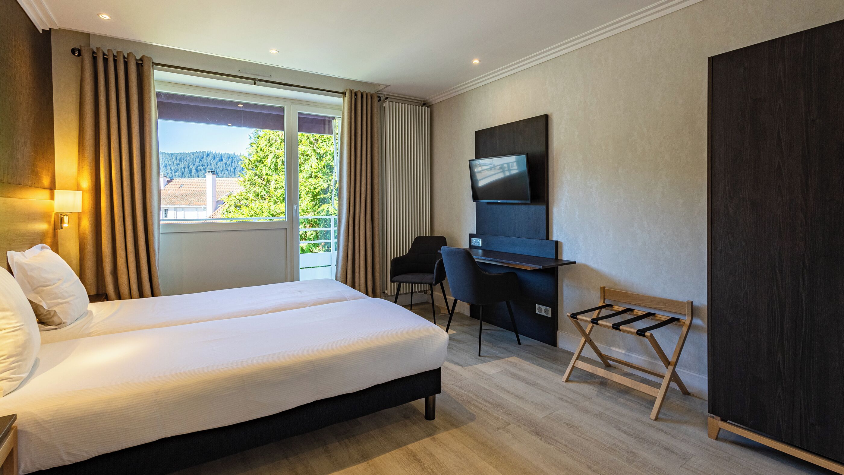 Habitación de hotel con una cama grande, un escritorio, un televisor y vistas a zonas verdes.