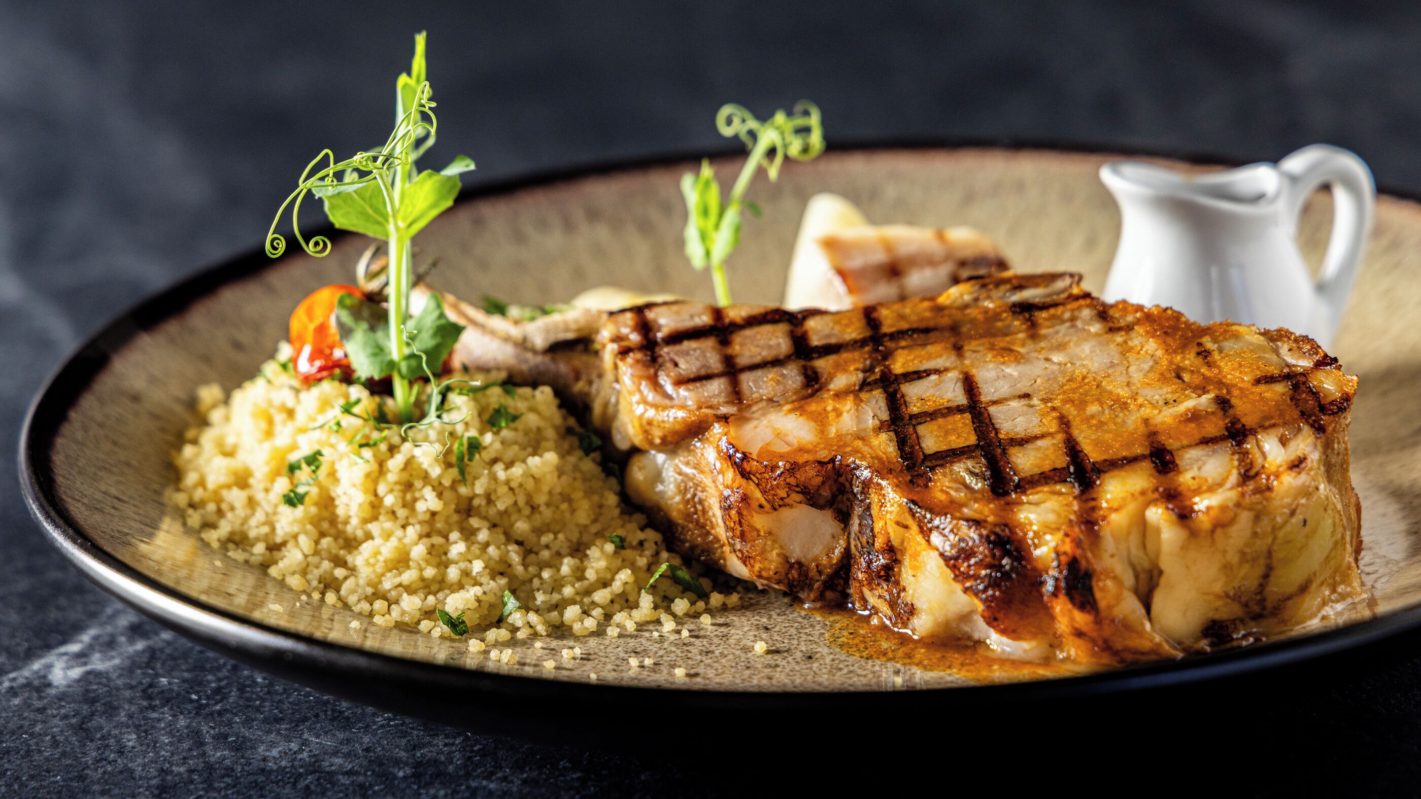 Ein Teller mit gegrilltem Hähnchen, Kuskus und Gemüse.
