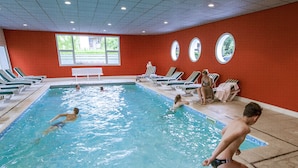 An indoor swimming pool with multiple lanes, lounge chairs, and a red wall with windows. - Hôtel Beau Rivage (Gerardmer)
