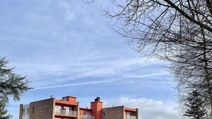 A multi-story building with balconies, a well-maintained lawn, and a clear sky. - Le Relais De Montigny - Logis (Montigny)