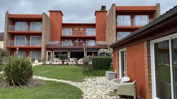 A multi-story building with balconies, a stone pathway, and outdoor seating.