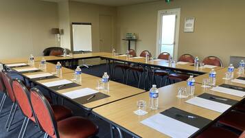 A conference room with long tables, chairs, water bottles, and a whiteboard.