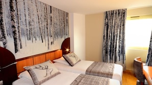 Quarto de hotel com duas camas, uma pintura grande na parede e uma janela com cortinas.