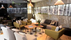 Um hall de hotel moderno com área de estar, balcão de recepção e um grande mural na parede.
