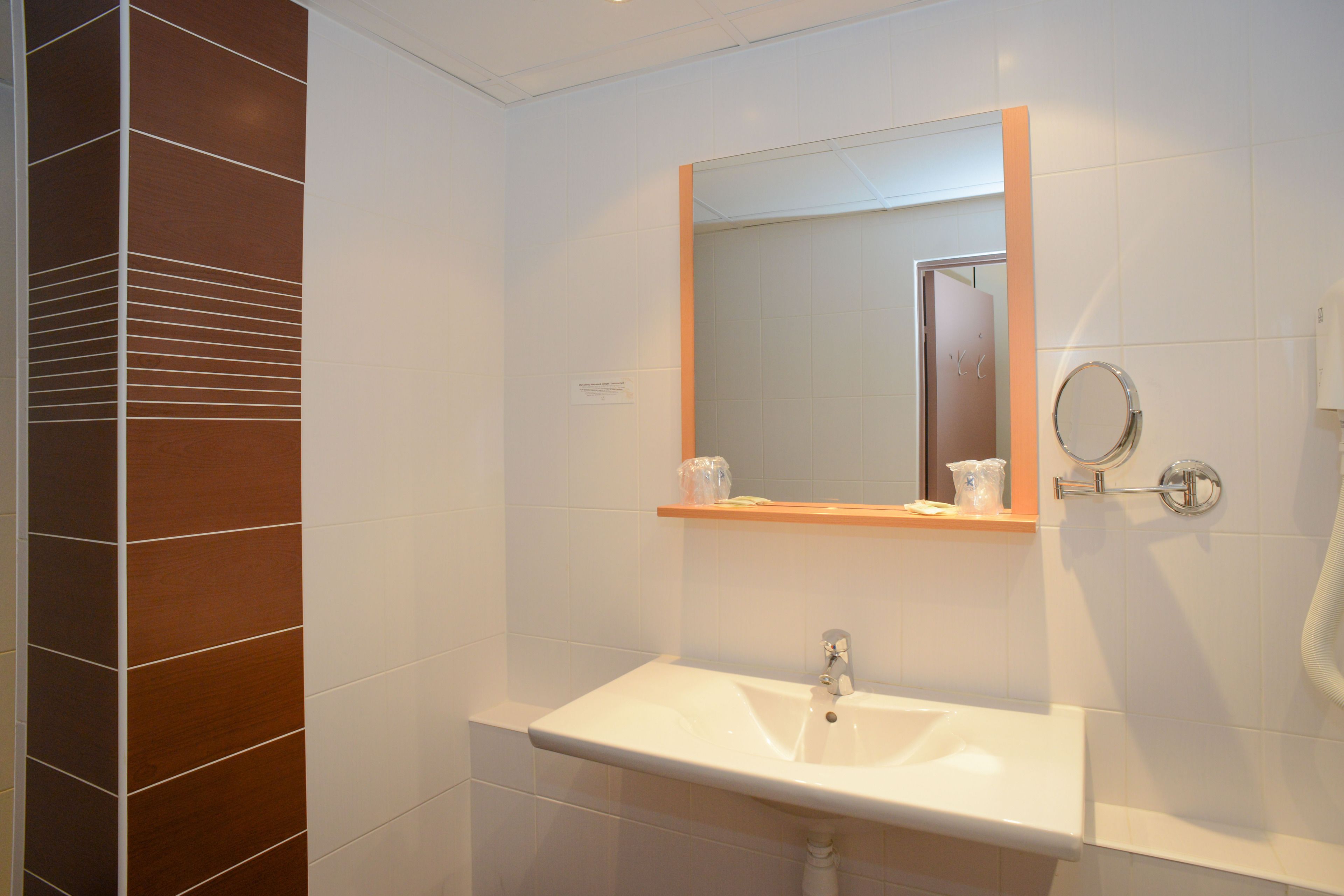 Un baño con un lavamanos blanco, un espejo y un perchero para toallas.