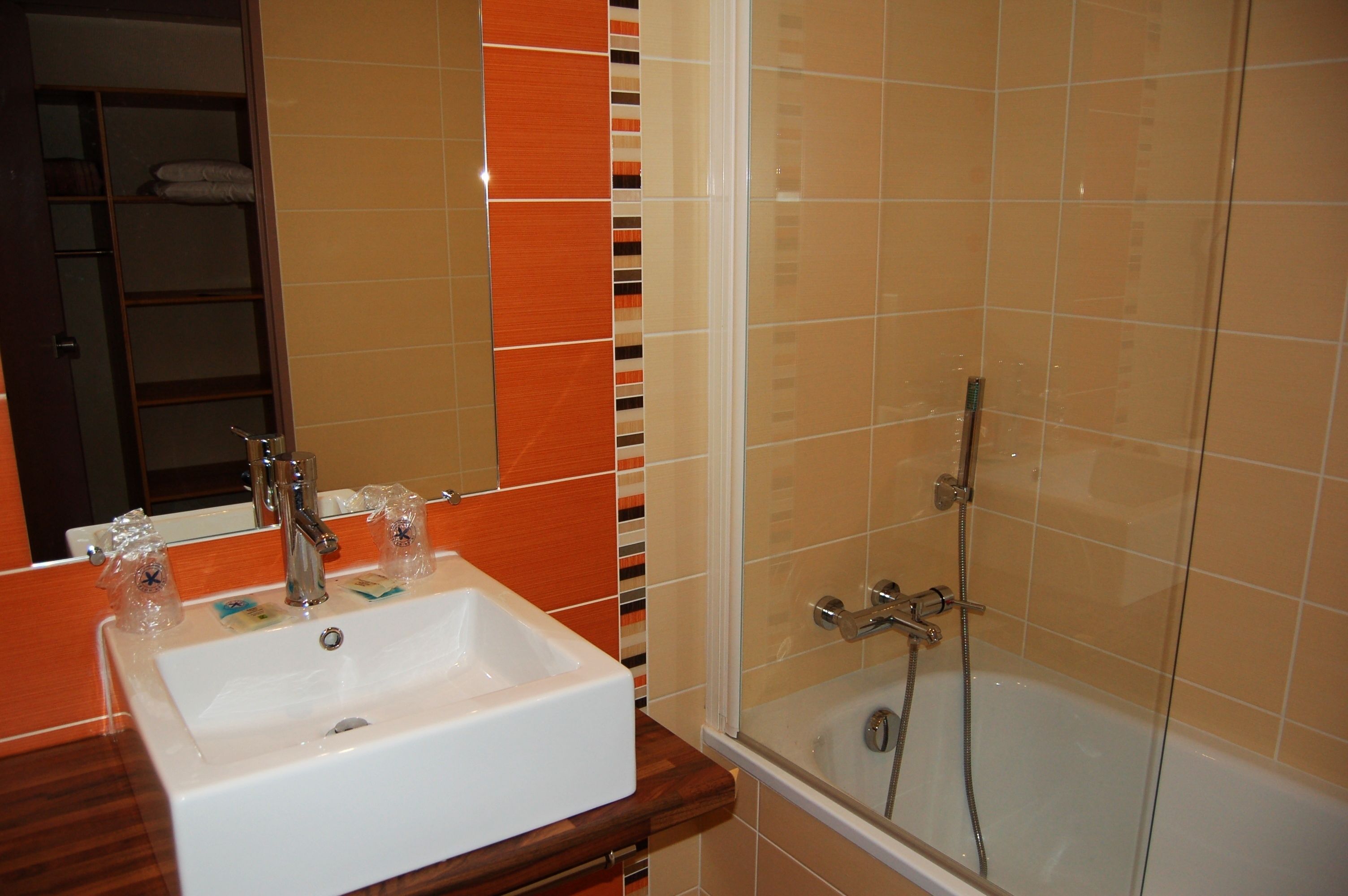 A bathroom with a white sink, a mirror, and a glass-enclosed shower area.