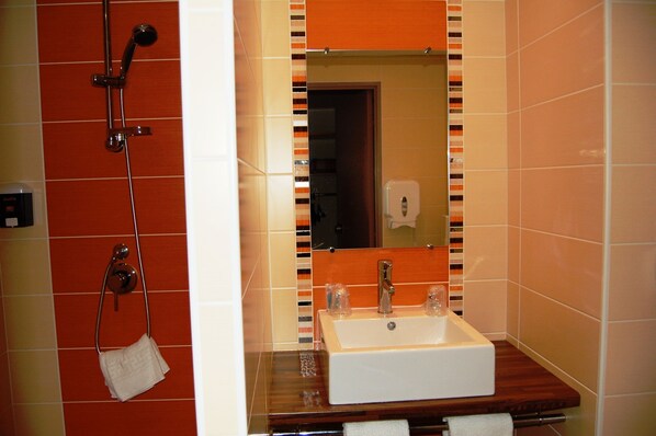 Un baño con ducha, lavamanos y espejo.
