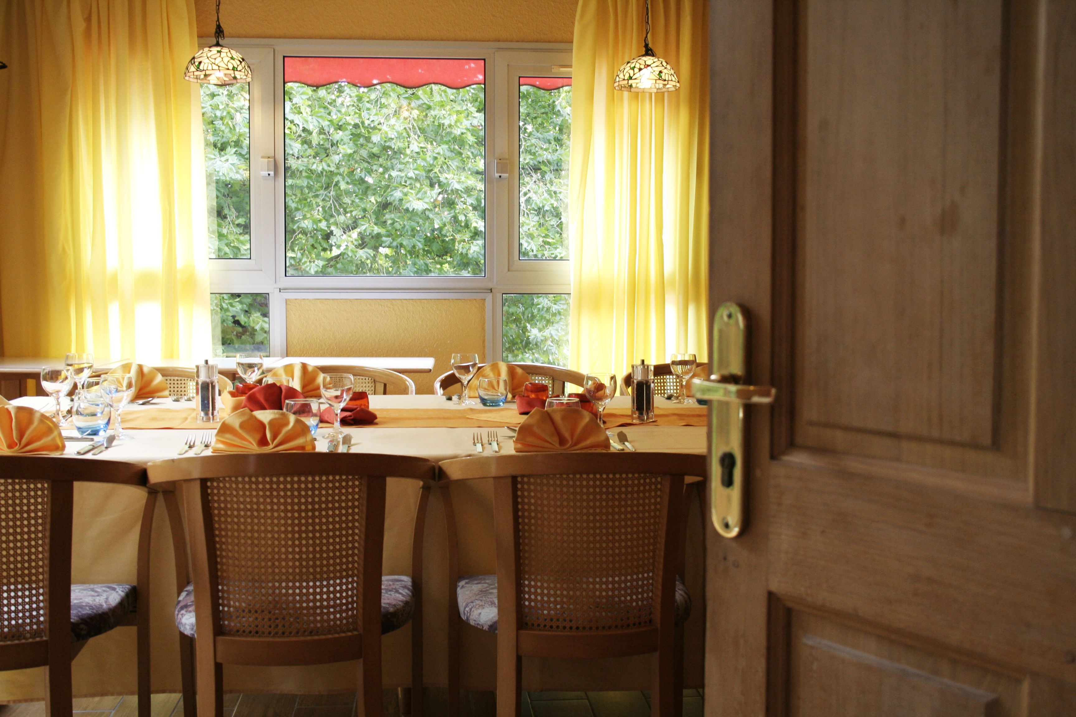 Ein Essbereich mit einem Tisch für vier Personen, Holzstühle und einem Fenster mit Vorhängen.