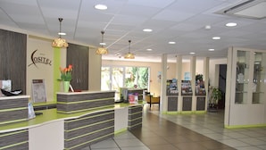 A reception area with a reception desk, a wall-mounted sign, a potted plant, and a glass display cabinet. - Hôtel Cositel Coutances (Coutances)