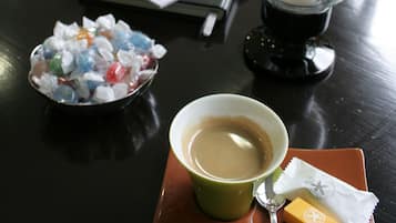 Une table avec une bougie, une tasse de café, un bol de cubes de gelée et un paquet de collations.