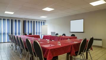 Ein Konferenzraum mit Tischen, Stühlen, einer Projektionsleinwand und einer Whiteboard.