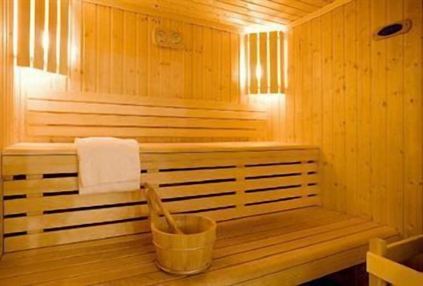 Una sauna de madera con un banco y un balde de madera.