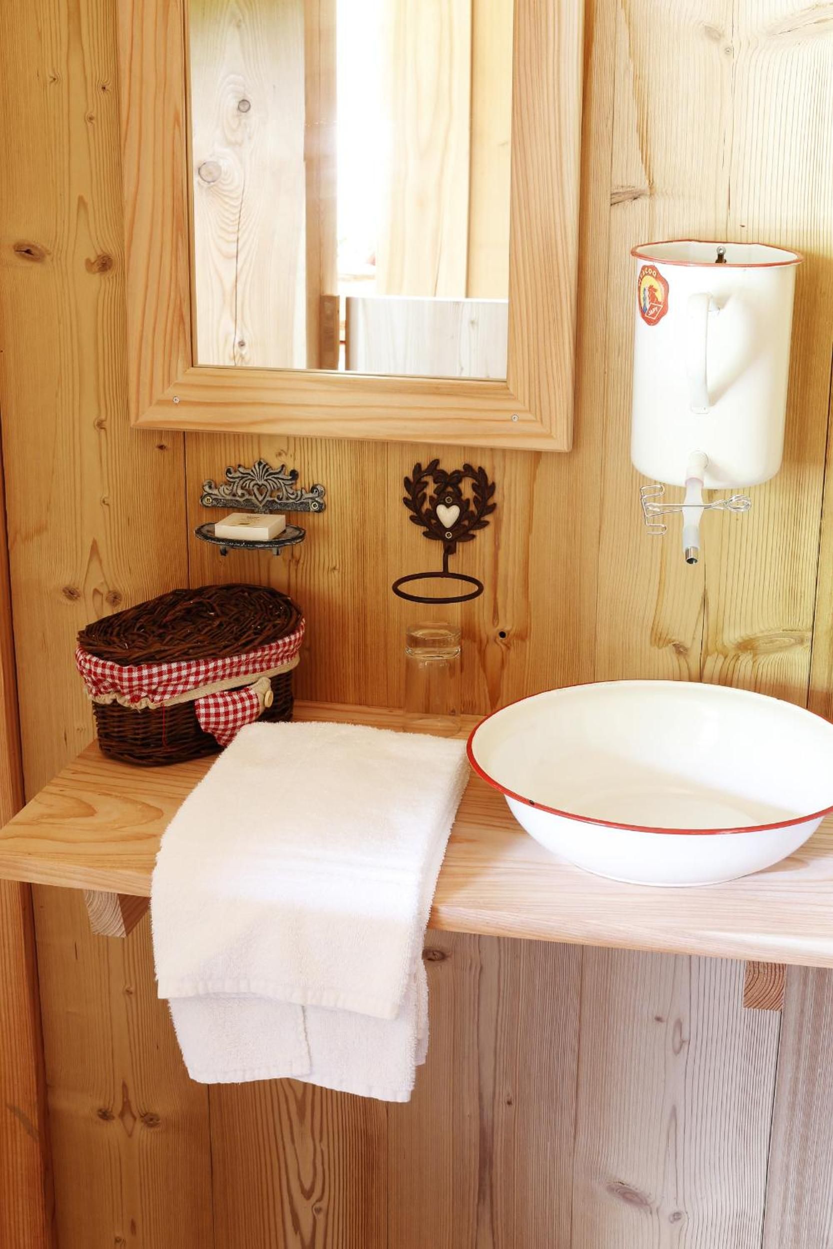 Une salle de bain en bois avec un lavabo blanc, un miroir et un porte-serviettes.