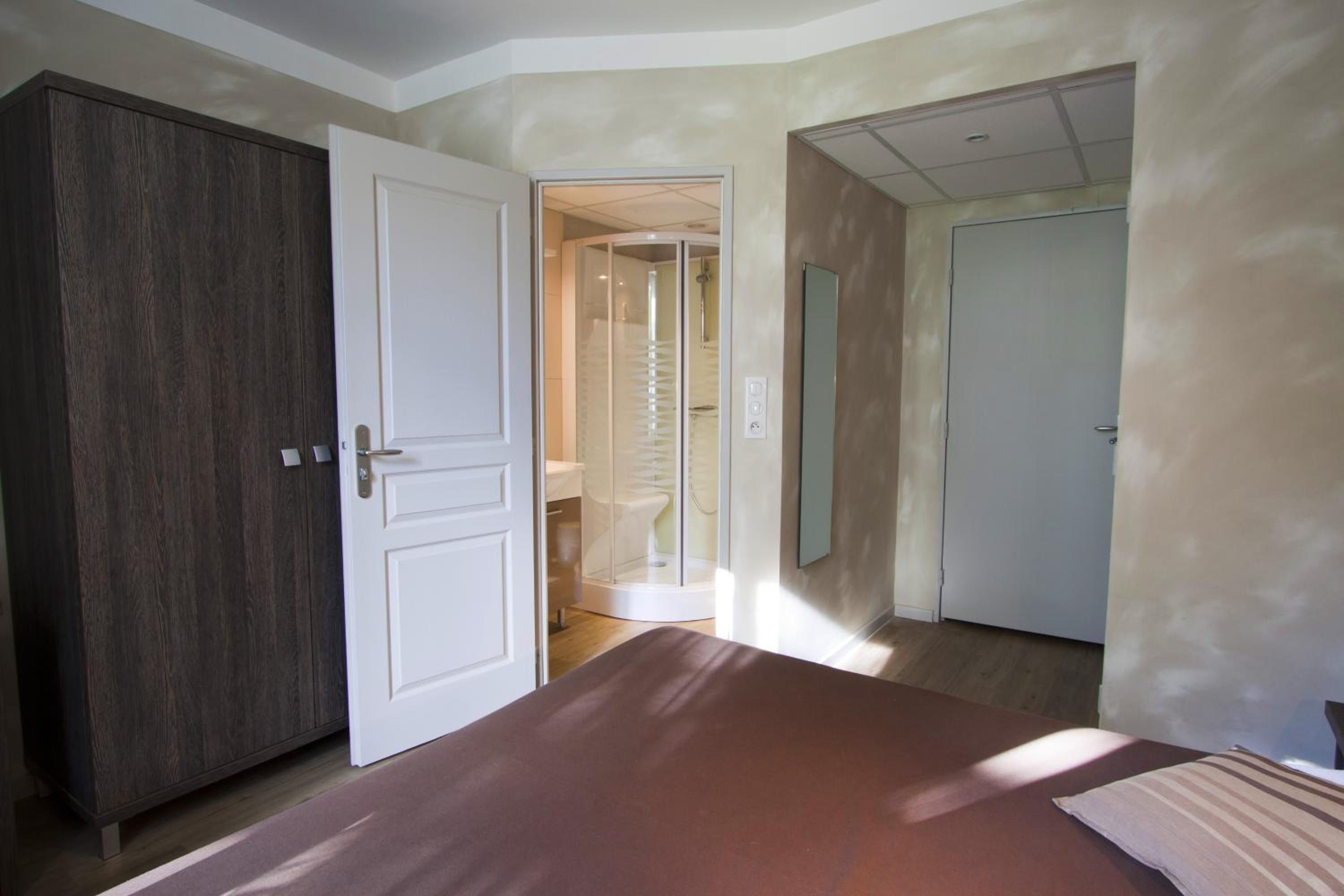 Un dormitorio con cama, armario y baño con ducha.
