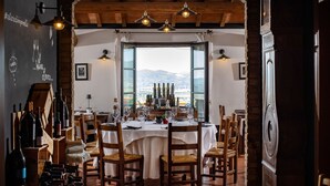 A dining area with a table set for six, wooden chairs, and a view of the mountains through large windows.