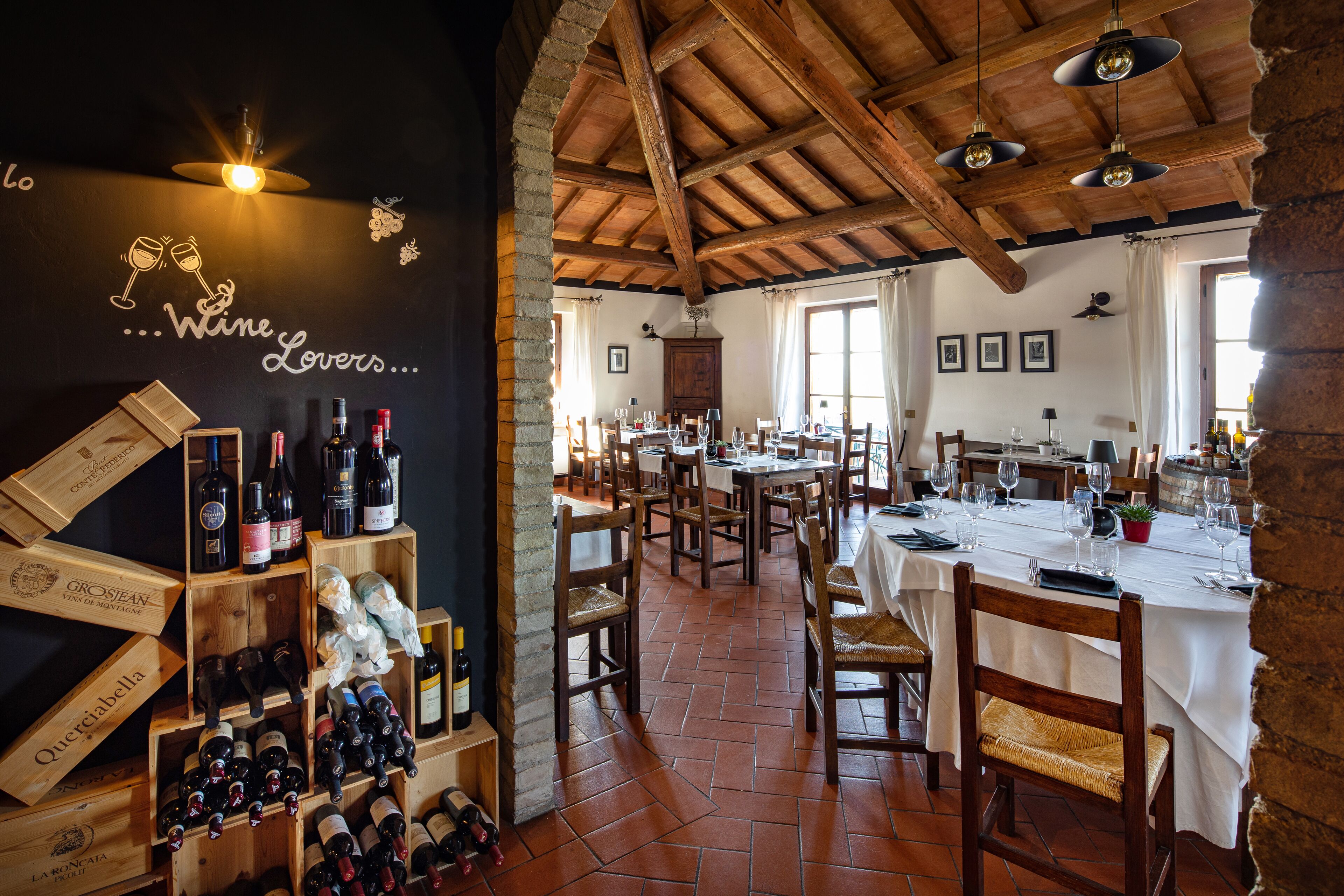 A restaurant with wooden beams, wine racks, and tables set for dining.