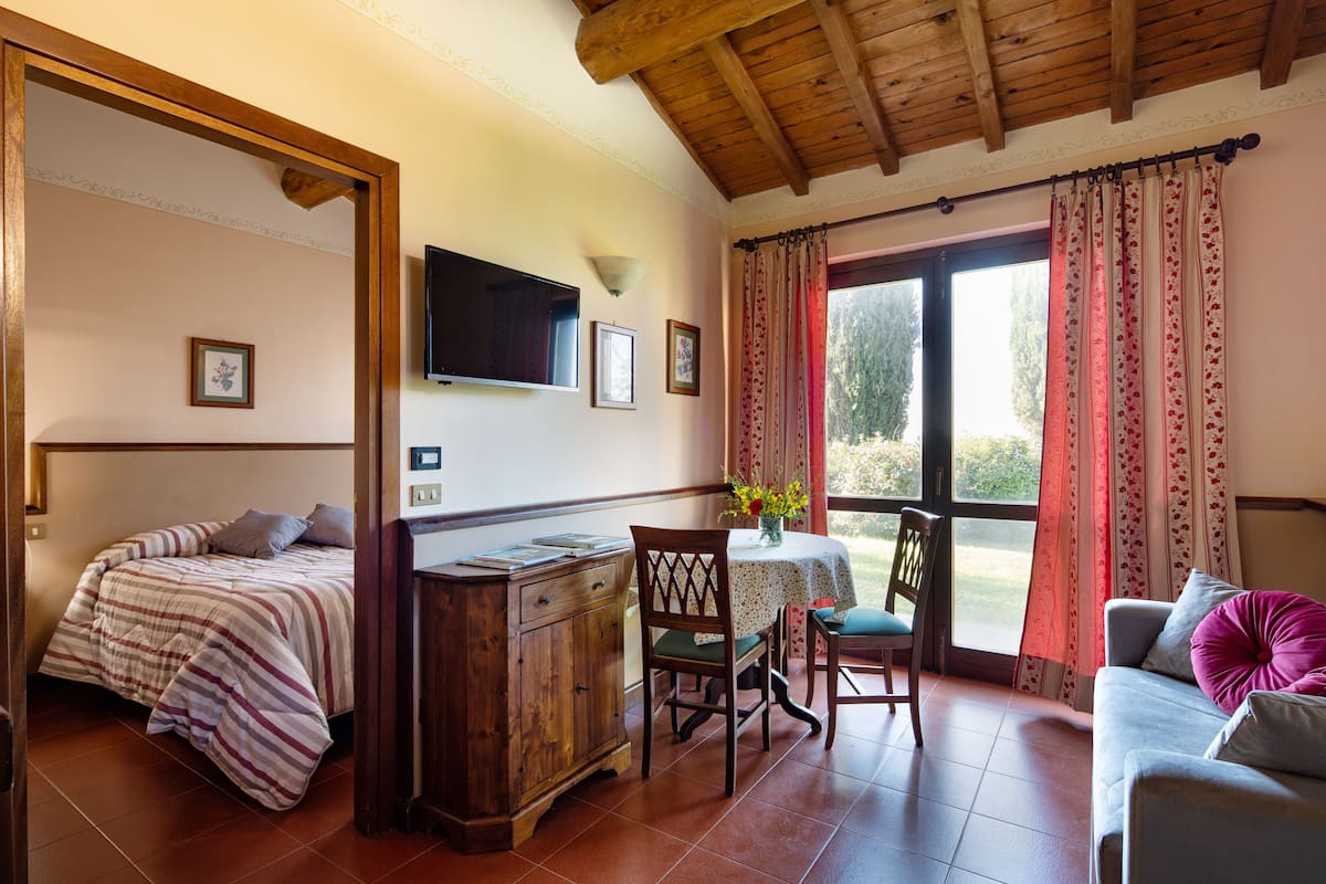 Une pièce confortable avec un lit, une armoire en bois, une table à manger avec des chaises et un canapé.