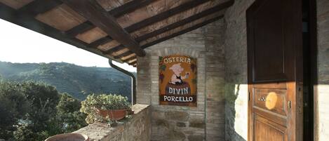 A stone building with a wooden door and a sign that reads "Osteria Divin Porcello".