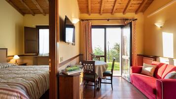 Une chambre d’hôtel avec un lit, un bureau avec des livres, un canapé rouge et une table avec des chaises.