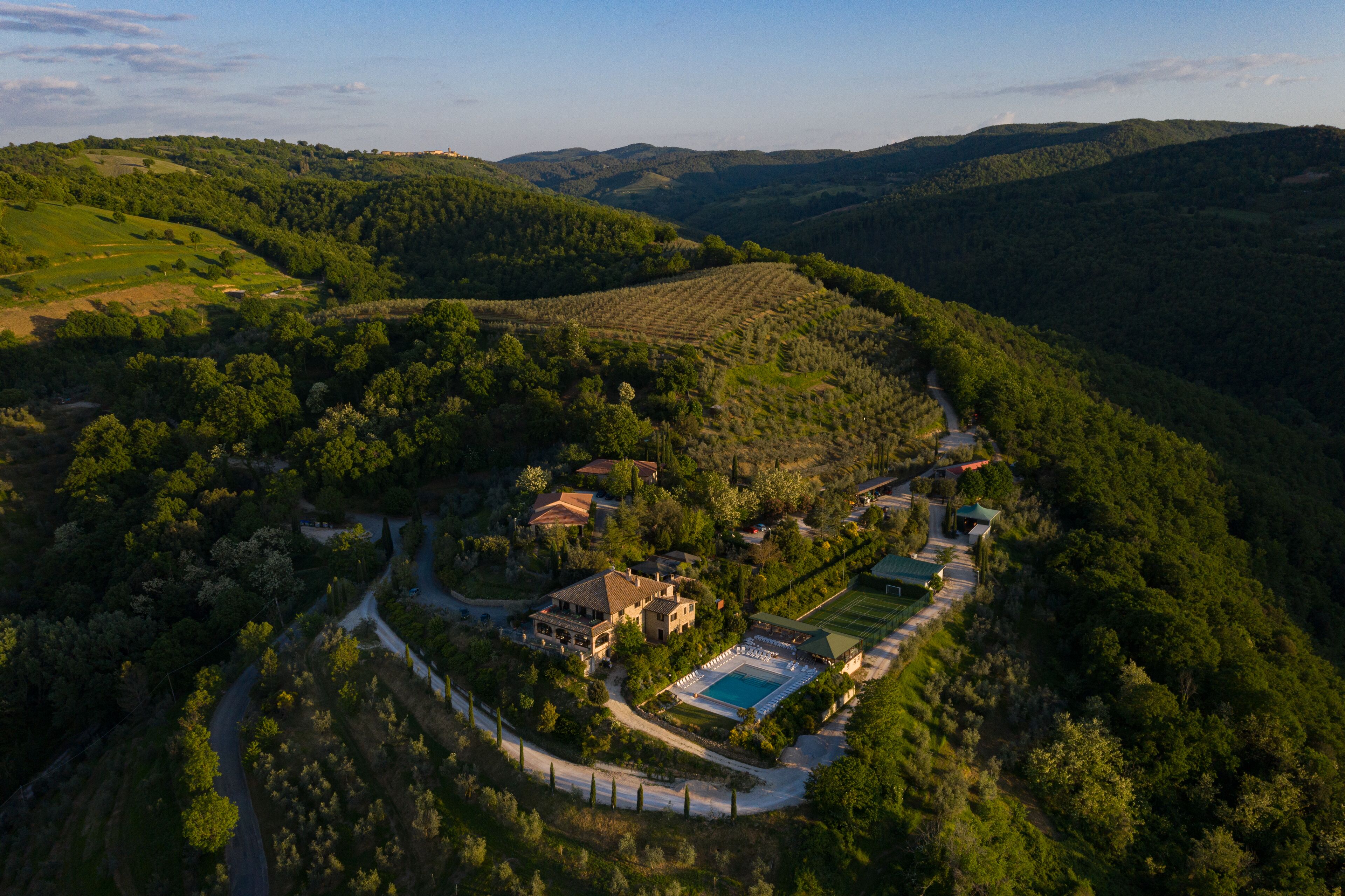 Vista aérea de una propiedad con piscina, varios edificios y vegetación circundante.