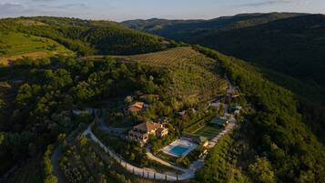 Vista aérea de una propiedad con piscina, varios edificios y vegetación circundante.