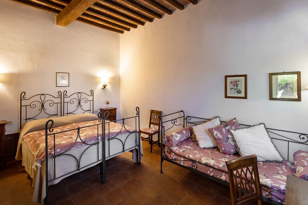 Une chambre à coucher avec deux lits en métal, une chaise en bois et un canapé.