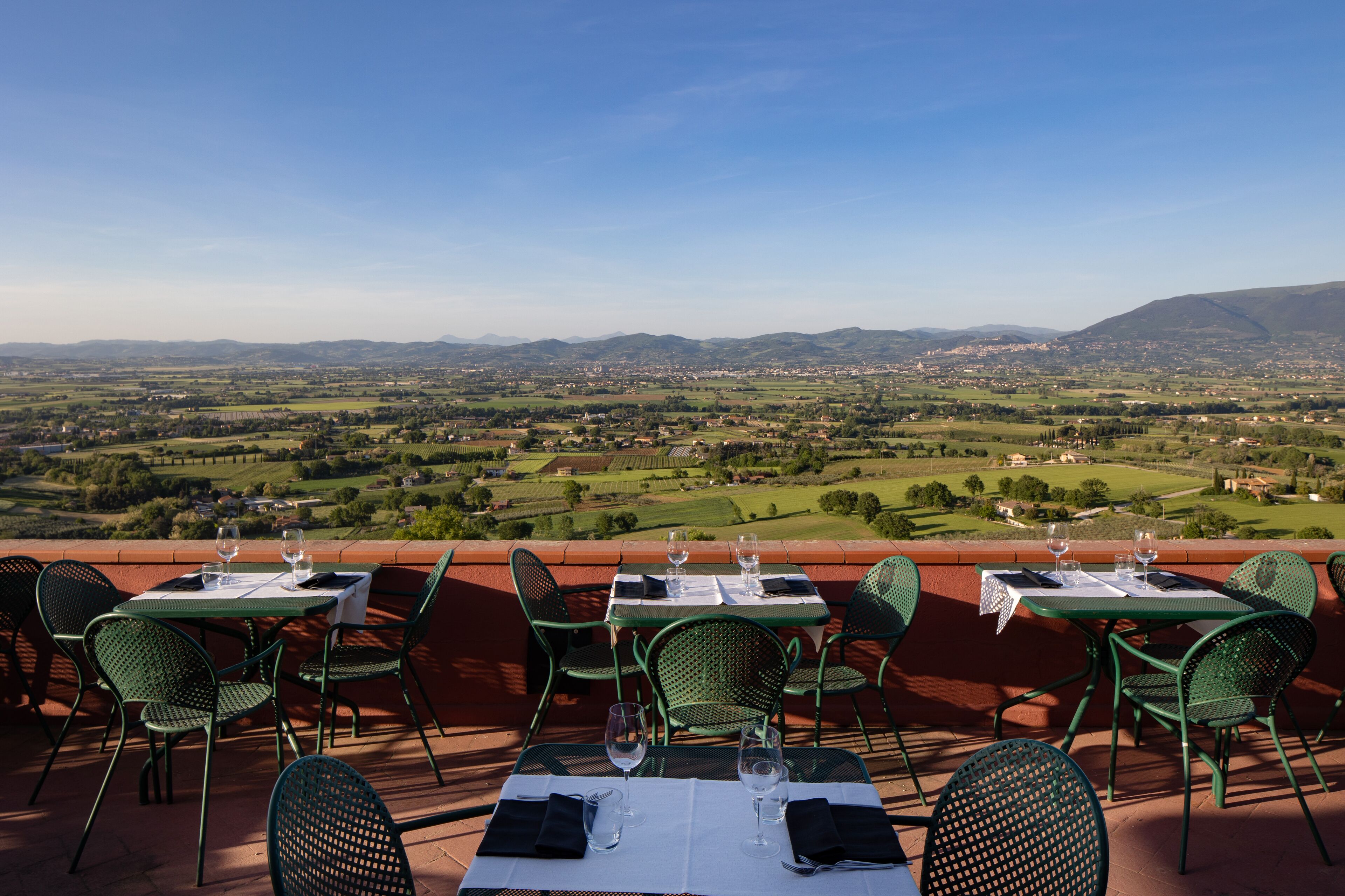 Una terraza con una mesa lista para dos personas, con vistas a un paisaje pintoresco.