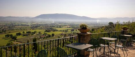 Una terraza con asientos al aire libre, vistas al campo y una montaña distante.