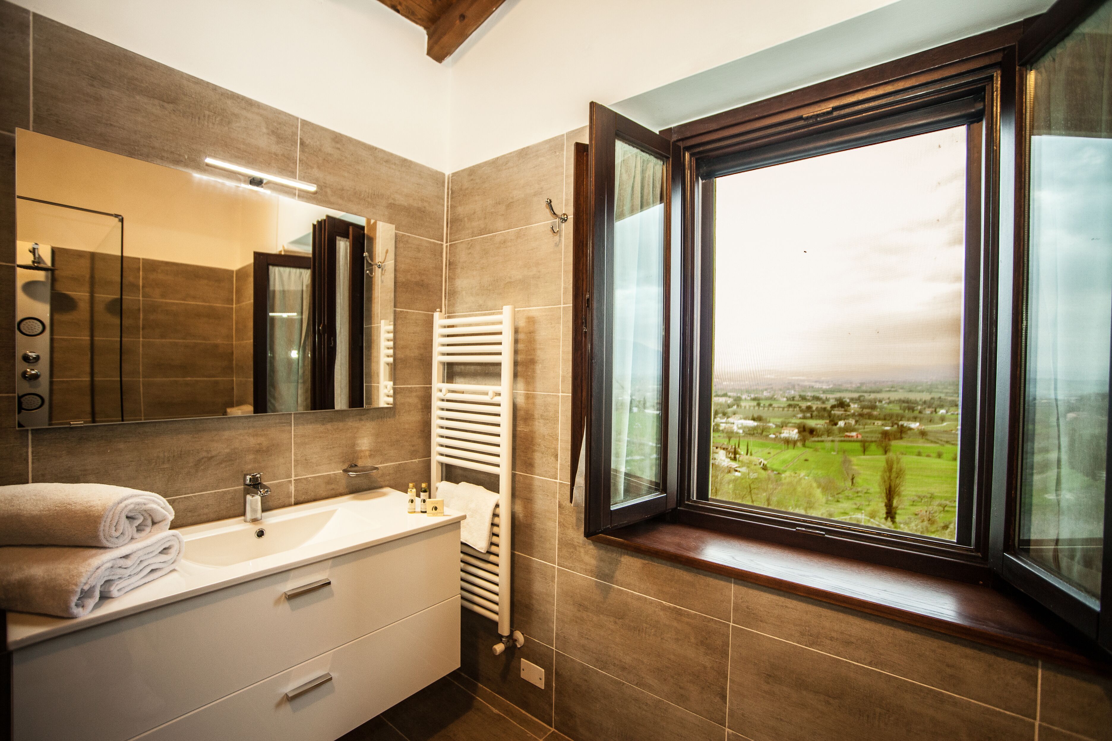 Une salle de bain moderne avec une grande fenêtre, un lavabo blanc et un porte-serviettes.